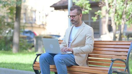 Middle Aged Man Working on Laptop Outdoor
