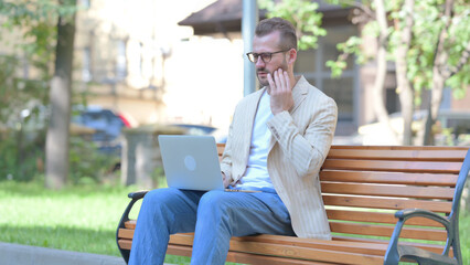 Middle Aged Man with Toothache Working on Laptop Outdoor