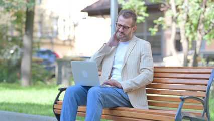 Middle Aged Man with Neck Pain Working on Laptop Outdoor