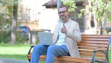 Thumbs Up by Middle Aged Man on Laptop Outdoor