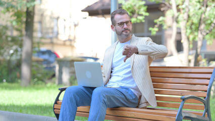 Thumbs Down by Middle Aged Man Working on Laptop Outdoor