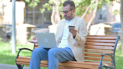 Middle Aged Man Upset by Online Payment Failure on Laptop Outdoor - obrazy, fototapety, plakaty