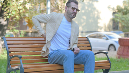 Fototapeta premium Modern Casual Man Sitting Outdoor with Back Pain