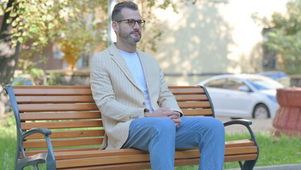 Obraz premium Modern Casual Man Sitting Outdoor on Bench