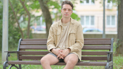 Obraz premium Casual Young Man Looking at Camera while Sititng Outdoor