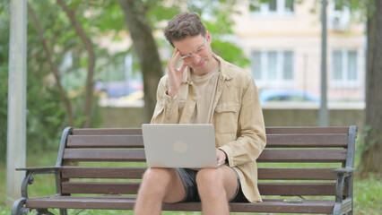 Fototapeta premium Casual Young Man with Headache Working on Laptop Outdoor
