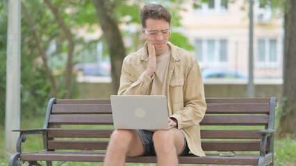 Casual Young Man with Toothache Working on Laptop Outdoor