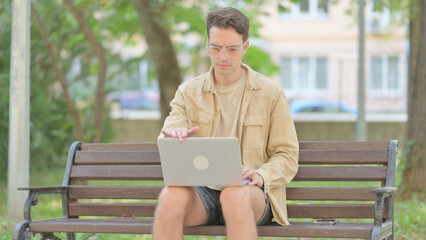 Modern Young Man Closing Laptop and Leaving Bench Outdoor