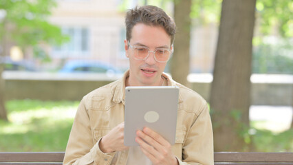 Casual Young Man Doing Video Chat on Tablet Outdoor