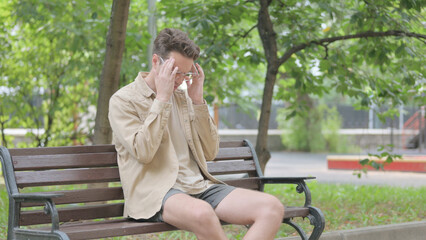 Modern Young Man with Headache Sitting on Bench