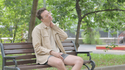 Obraz premium Modern Young Man with Neck Pain Sitting on Bench
