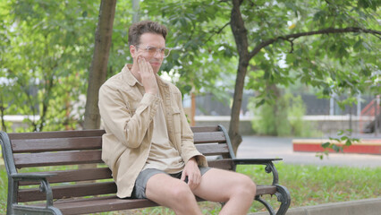 Modern Young Man with Toothache Sitting on Bench
