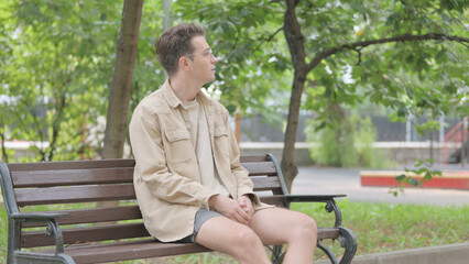 Obraz premium Modern Young Man Coming and Sitting on Bench in Park
