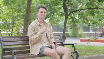Obraz premium Thumbs Up by Modern Young Man Sitting Outdoor