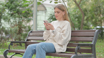 Obraz premium Casual Young Woman using Phone while Sitting Outdoor