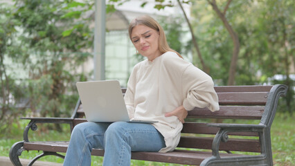 Fototapeta premium Casual Young Woman Using Laptop with Back Pain while Sitting Outdoor