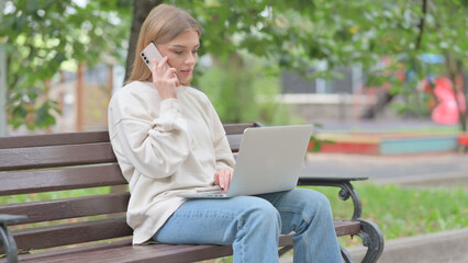 Young Woman Talking on Phone and Using Laptop Outdoor
