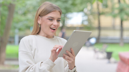Fototapeta premium Woman Celebrating Success on Tablet Outdoor