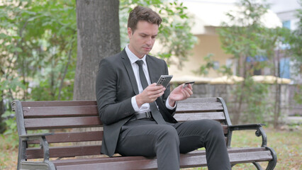 Obraz premium Young Businessman Shopping Online while Sitting Outdoor