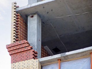 Reinforced concrete columns and monolithic floor slabs, exterior brick wall in progress. A residential high-rise building under construction