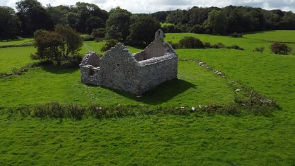 Aerial view establishing reveal Capel Lligwy ruined chapel on Anglesey island coastline, North Wales