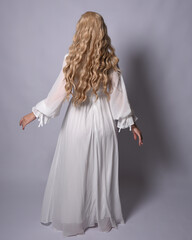 Full length portrait of blonde woman  wearing  white historical bridal gown fantasy costume dress. Standing pose, facing backwards walking away from camera, isolated on studio background.