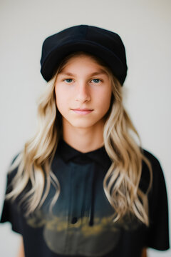 Image of a head shot of a cute white Caucasian 14 year old skater boy with long  blonde hair. He is wearing a black cap.