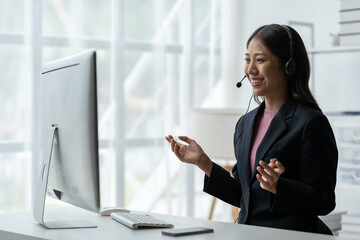 Asia call center with headset and microphone working on laptop Female entrepreneurs serving...