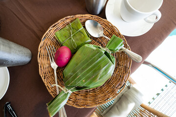 binalot, it's a filipino dish wrapped and cooked in banana leaf, it can be pork, chicken or seafood and served with salted eggs, tomatoes and onions