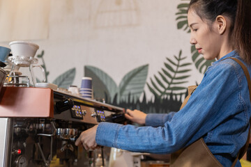 Side view, young attractive Asian barista female using professional coffee machine to make hot espresso coffee to mug in cozy cafe, small business owner start-up for young people lifestyle concept