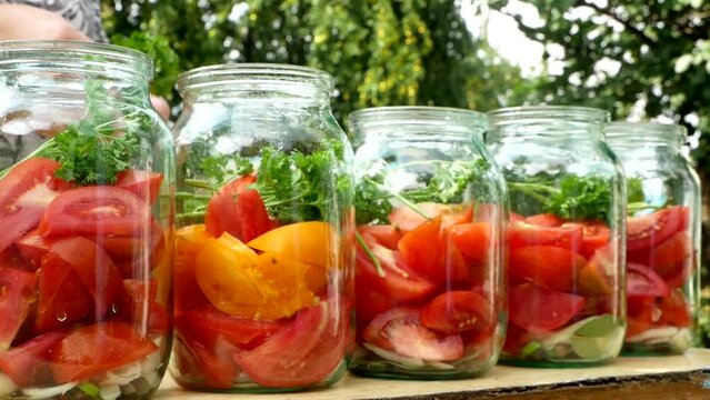 Preservations, conservation. Salted, pickled tomatoes in a jars on an wooden table. Pickling tomatoes at home. Vegetable harvest conservation. Close up.