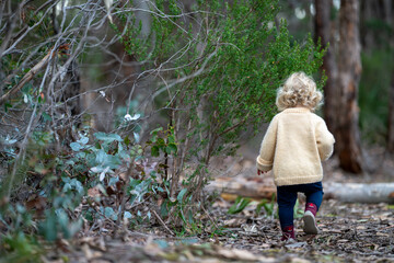 blonde todder walking in a forest on a hike in spring