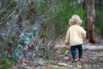 blonde todder walking in a forest on a hike in spring