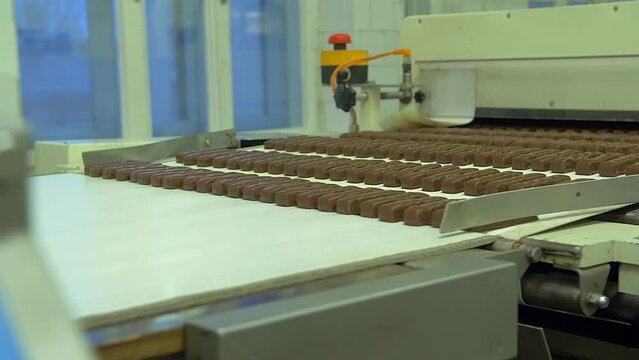 dolly slow motion medium shot of freshly made chocolate bars moving from a slower conveyor line to a faster one