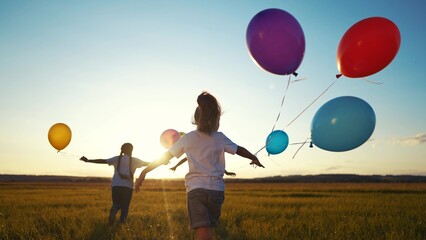 children in balloons in the park. children run in nature in park with balloons. happy family kid holiday concept. children view from back silhouette run in nature at dream sunset holding balloons © maxximmm