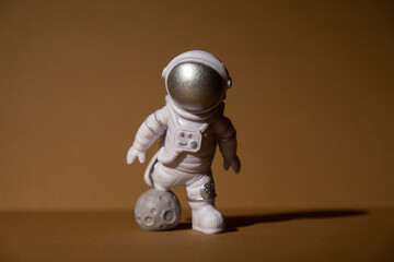 Plastic toy figure astronaut on beige neutral background Copy space. Concept of out of earth travel, private spaceman commercial flights. Space missions and Sustainability