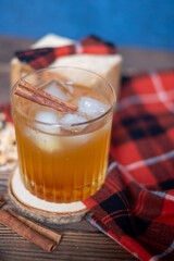 Lumberjack cocktail, a glass of whiskey with ice and a cinnamon stick on a wooden tray, a checkered Lumberjack bow and plaid. Copy space