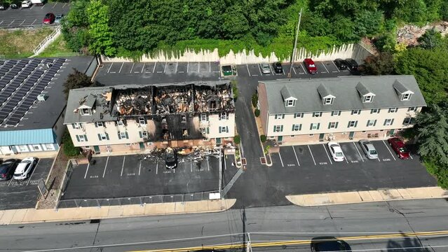 An apartment complex with a unit burned and collapsed after fire. Aerial orbit on summer day.