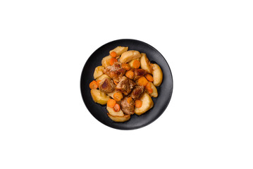 Beef meat and vegetables stew on a black plate with roasted potatoes