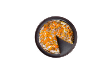 Delicious fresh liver cake with mayonnaise and carrots on a black plate against a dark concrete...