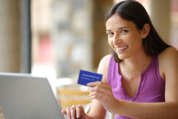 Happy woman looks at camera buying online in a bar