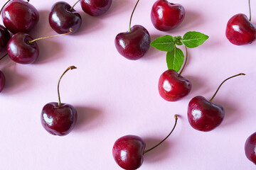 Red cherries on a pink background. Flat lay, top view.