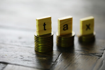 Tax Concept with wooden block on stacked coins
