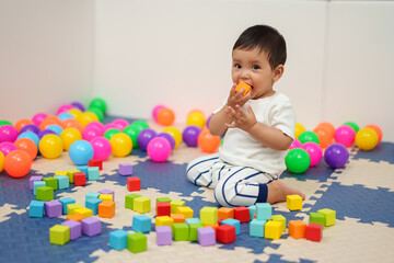 Fototapeta na wymiar infant baby biting wooden block toy in playpen