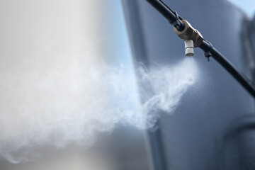 Sprinkler head from a high pressure outdoor cooling system for cafe, close-up, copy space.