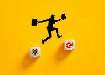 Silhouette of a businessman jumping from idea to growth symbol on wooden cubes.