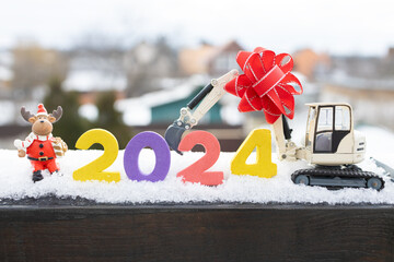 model of a toy excavator, souvenir deer, New Year 2024 numbers in the snow. card for Christmas...