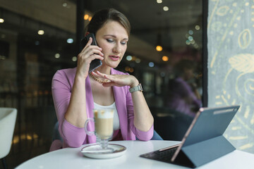 Business negotiations on the phone in a cafe of a young woman entrepreneur.