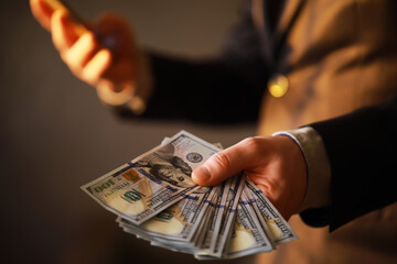 Business Man Displaying a Spread of Cash over a gray vintage background