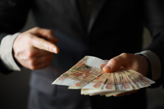 a man in an expensive suit holds a lot of money in his hand, Russian rubles, bills of five thousand rubles